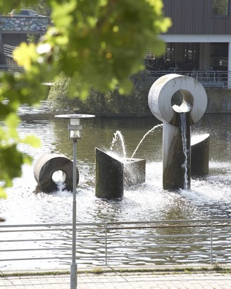 Albertslund Rådhus med rådhussøen og træer i forgrunden.