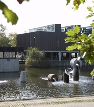 Albertslund Rådhus med rådhussøen og træer i forgrunden.