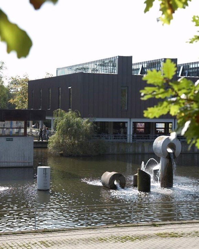 Albertslund Rådhus med rådhussøen og træer i forgrunden.